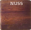 A close-up of a wooden surface with the word "NUSS" printed on it. Anteprima dell’immagine prodotto