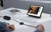 A person's hands are shown on a desk, interacting with a charging cable connected to a power adapter and a tablet with a keyboard. The tablet is displaying a video. Náhled obrázku produktu