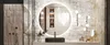 A modern bathroom vanity with a large round LED mirror, a black rectangular sink with a gold faucet, and decorative items on the counter. Voir les images du produit