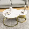 A set of two round coffee tables with marble-look tops and gold metal frames, placed on a rug next to a sofa.