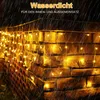 Icicle lights are hanging on a brick wall during a rain shower. Produktbild-Vorschau