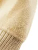 A close-up view of a fuzzy, beige knitted fabric, possibly a sweater or hat, with a ribbed edge visible at the bottom. Produktbild-Vorschau