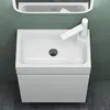 A white bathroom sink and vanity set against a green wall and dark floor. Produktbild-Vorschau