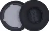 Two black ear pads for headphones are shown against a white background. One ear pad is shown from the side, revealing its inner mesh and attachment rim. The other ear pad is shown from the front, with a textured pattern in the center. Náhľad obrázku produktu