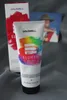 A tube of Goldwell Elumen Play hair color and its packaging are displayed on a gray fabric surface. A small promotional card with a person wearing a hat is in the background. Produktbild-Vorschau