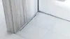 A close-up view of a shower drain profile installed on a tiled floor next to a marble wall. Náhľad obrázku produktu