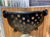 A black plastic hay feeder with circular holes is mounted on a wooden wall in a stable. Produktbild-Vorschau