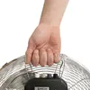 A hand grips the handle of a large fan. Voir les images du produit