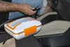 A person's hand is holding a car charger plug near a portable lunchbox inside a car. Náhled obrázku produktu