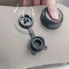 A close-up of an inflatable pillow's valve with a hand pressing down on the cap. Produktbild-Vorschau