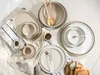 A collection of ceramic tableware, including plates, bowls, and cups, arranged on a white surface with some light shadows. Náhľad obrázku produktu