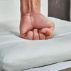 A fist pressing into a white cushioned surface. Produktbild-Vorschau