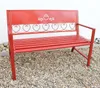 A red metal garden bench with heart-shaped decorative elements on a gravel surface in front of a white wall. Produktbild-Vorschau