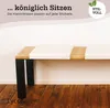 A close-up view of a wooden bench with white seat cushions, set against a white wall and a wooden floor. Produktbild-Vorschau
