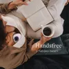 A person is reading a book and holding a cup of coffee while using a breast pump. Produktbild-Vorschau
