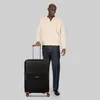 A man stands next to a black trolley suitcase. Podgląd zdjęcia produktu