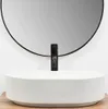 A white vessel sink with a black faucet in front of a round mirror. Anteprima dell’immagine prodotto