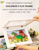 A hand is holding open a white flip frame displaying a child's drawing of a dinosaur and a volcano. Another child's drawing is partially visible to the left. Produktbild-Vorschau