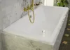 A close-up view of a white bathtub with gold fixtures, set against a marble-tiled wall and a patterned floor. Produktbild-Vorschau