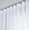 A close-up view of white sheer curtains hanging from a metal curtain rod. Produktbild-Vorschau