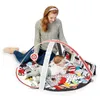 A woman is sitting on the floor next to a baby play mat, interacting with the baby. Podgląd zdjęcia produktu