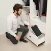 A man is kneeling in front of an open closet drawer, holding a black step stool. Anteprima dell’immagine prodotto