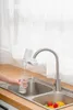 A person is filling a glass of water from a filtered faucet in a kitchen sink. Náhled obrázku produktu