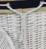 A close-up view of a white wicker basket with a navy blue and tan fabric lining, showing a white rope drawstring. Náhled obrázku produktu