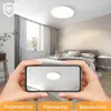A bedroom scene with a ceiling lamp, viewed through a smartphone screen held by hands. Voir les images du produit