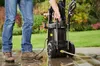 A person is using a pressure washer in a garden setting. Produktbild-Vorschau