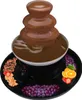 A chocolate fountain with various fruits and snacks arranged around it on a black platter. Podgląd zdjęcia produktu
