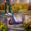 A person is using a hand truck to move a potted plant up a set of stone stairs in a garden. Anteprima dell’immagine prodotto