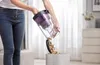 A person is emptying the dustbin of a vacuum cleaner into a trash can. Produktbild-Vorschau