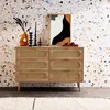 A wooden dresser with rattan drawer fronts is displayed against a terrazzo-patterned wall, adorned with decorative items. Anteprima dell’immagine prodotto