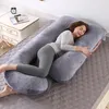 A woman is sleeping on a large U-shaped pillow on a bed. Náhled obrázku produktu