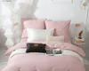 A neatly made bed with pink bedding, pillows, and a decorative black and gold pillow. Podgląd zdjęcia produktu