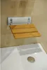A wall-mounted shower seat made of bamboo slats and a silver metal frame, installed above a white bathtub. Podgląd zdjęcia produktu