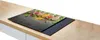 A glass stovetop cover with a spice design is placed on a modern induction stovetop, which is on a wooden countertop. Podgląd zdjęcia produktu