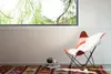 A chair and decorative items in a room with a large window overlooking greenery. Náhľad obrázku produktu
