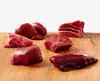 Several pieces of raw meat are arranged on a wooden cutting board. Náhľad obrázku produktu