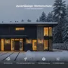 A modern house exterior at night with snow on the ground and trees in the background. The house has warm lights on inside and exterior wall lights are visible. Produktbild-Vorschau