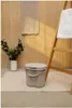 A bathroom scene with a diaper pail, plants, and towels. Produktbild-Vorschau