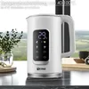 A white electric kettle with a digital display is shown on a countertop, with a blurred background of a window and greenery. Náhled obrázku produktu