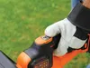 A gloved hand is pressing a button on the handle of a Black & Decker hedge trimmer. Anteprima dell’immagine prodotto