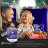 A woman and a girl are sitting in front of a Christmas tree, with the girl holding a gift. The scene is decorated for Christmas. Produktbild-Vorschau