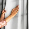 A person's hands are shown touching a white curtain. Produktbild-Vorschau