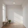 A bright, minimalist hallway with a large window, a wooden bench, and a ceiling light. Náhľad obrázku produktu