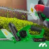 A person is using a green electric hedge trimmer to cut a bush, with leaves flying around. Podgląd zdjęcia produktu