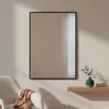 A mirror hanging on a wall above a shelf with a vase and a chair with a blanket. Anteprima dell’immagine prodotto