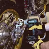 A person wearing work gloves is using a Makita impact wrench to work on a motorcycle's rear wheel assembly. Podgląd zdjęcia produktu